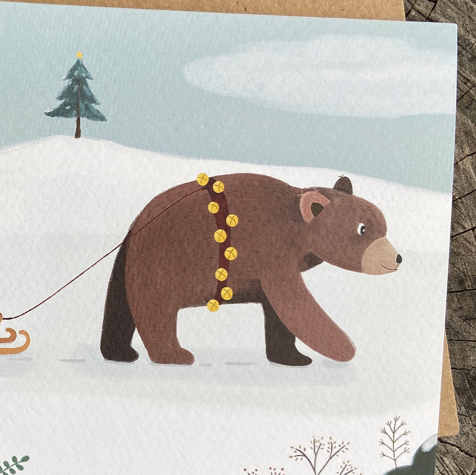 Card with a bear pulling a sled through a snowy landscape with trees.