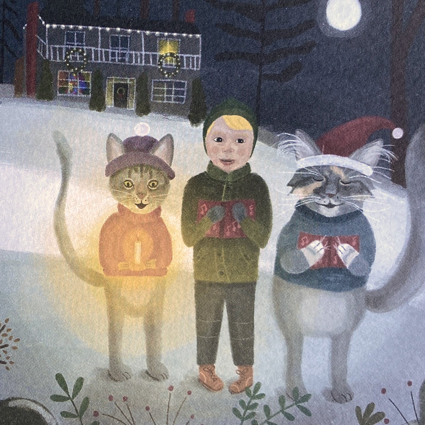 Illustration of a child with two cats wearing winter hats and scarves in a snowy night setting.