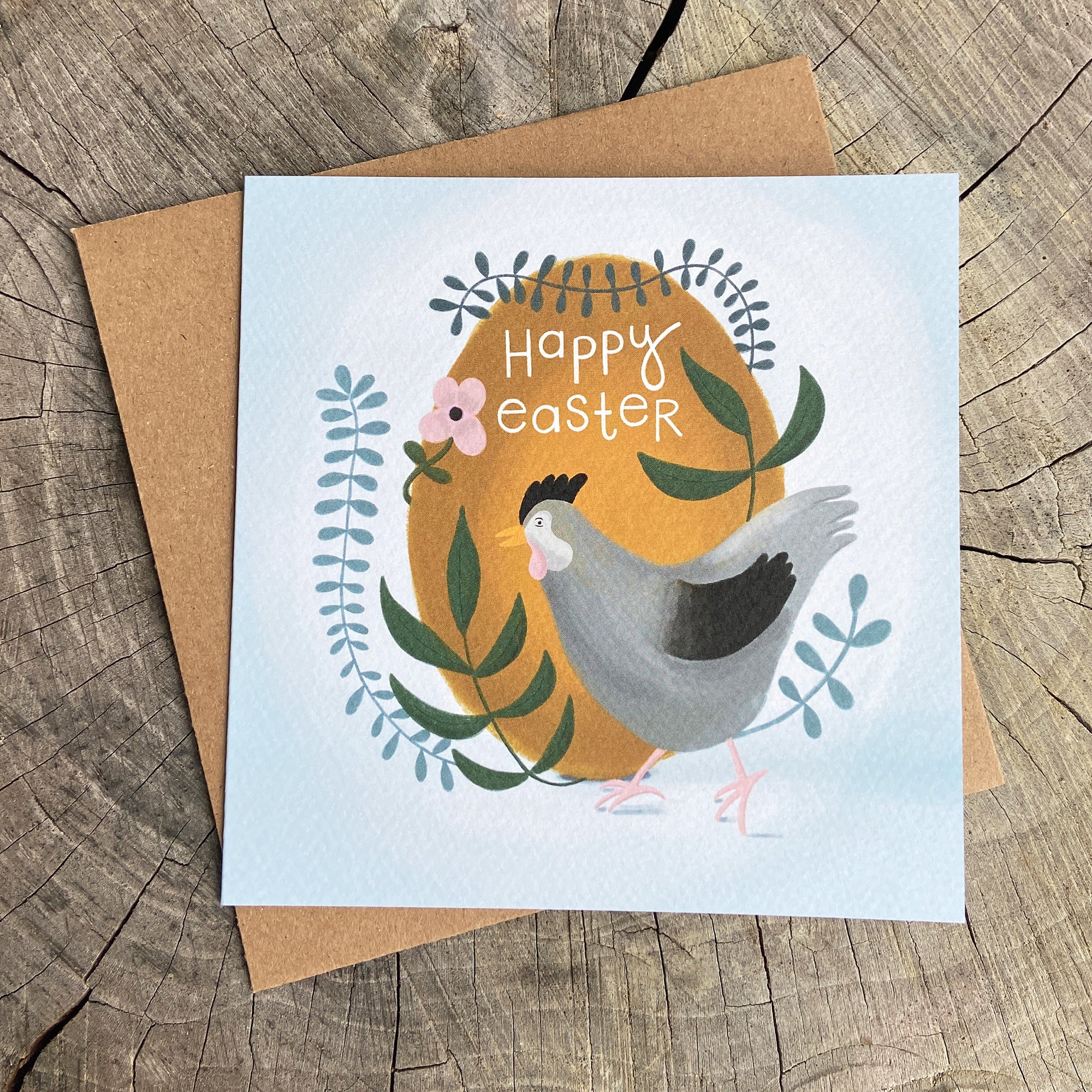 Easter greeting card with a chicken, egg and botanical illustration on a wooden surface