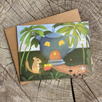 Greeting card with a teapot house and chipmunk illustration on a wooden surface
