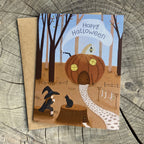 Halloween-themed greeting card with a pumpkin house, witch and black cat