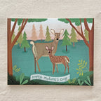 Card with two deer in a forest scene and 'Happy Mother's Day' banner on a textured surface.