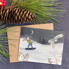 Holiday greeting card with a snowy scene of a person skiing with an owl, surrounded by pine branches and a pine cone.