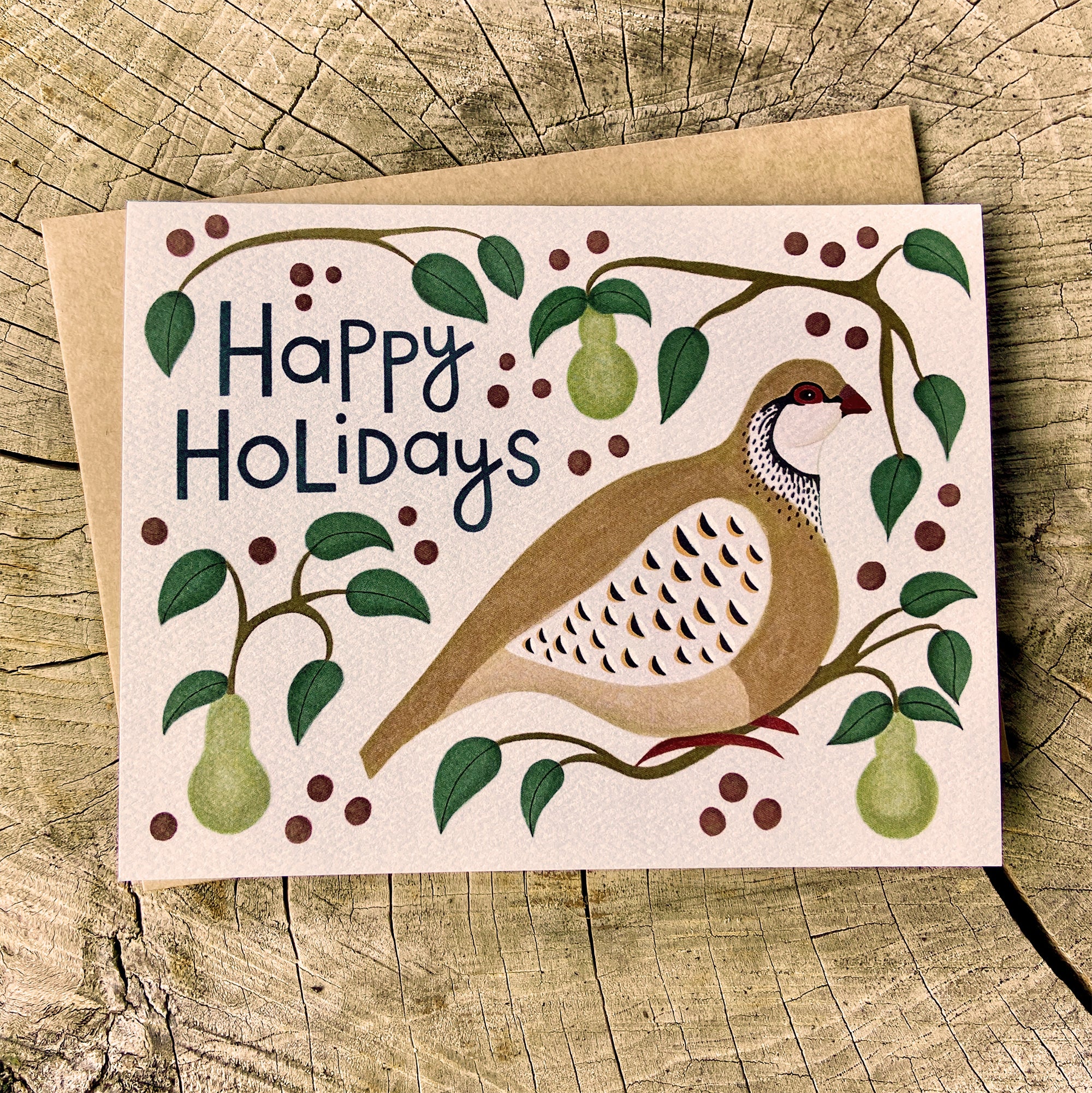Greeting card with a partridge in a pear tree illustration and 'Happy Holidays' text on a wooden background