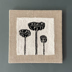 Textile art piece with black lotus pod designs on a white background and beige border.