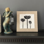 Decorative rabbit figurine with lantern and framed artwork of plants on a shelf.