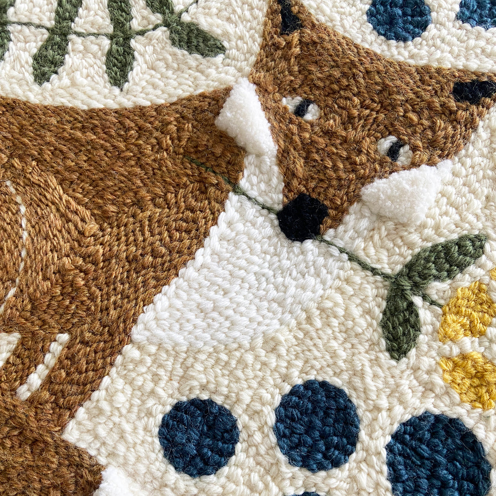 Close-up of a textured fabric art piece with a fox design and floral elements.