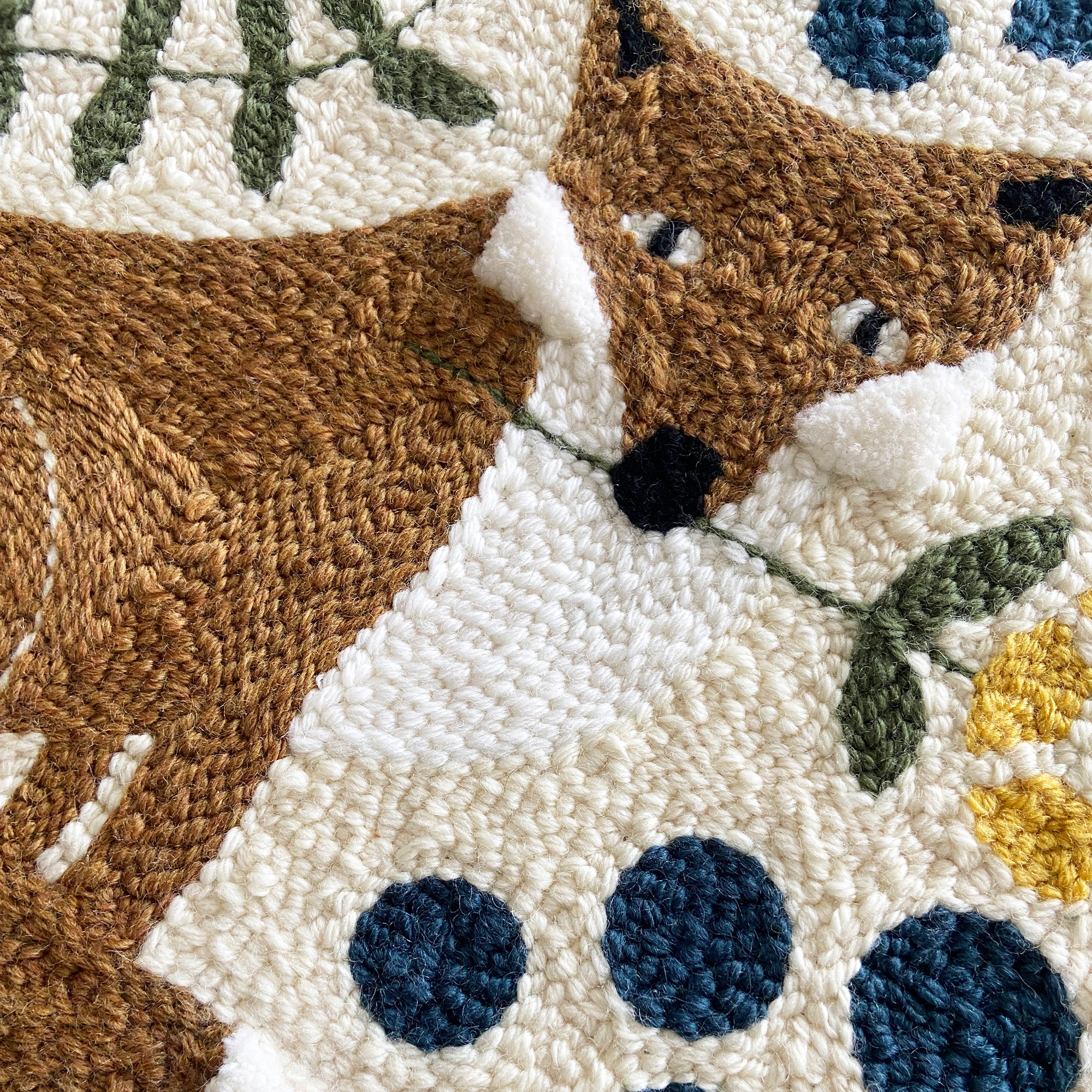 Close-up of a textured fabric art piece with a fox design and floral elements.