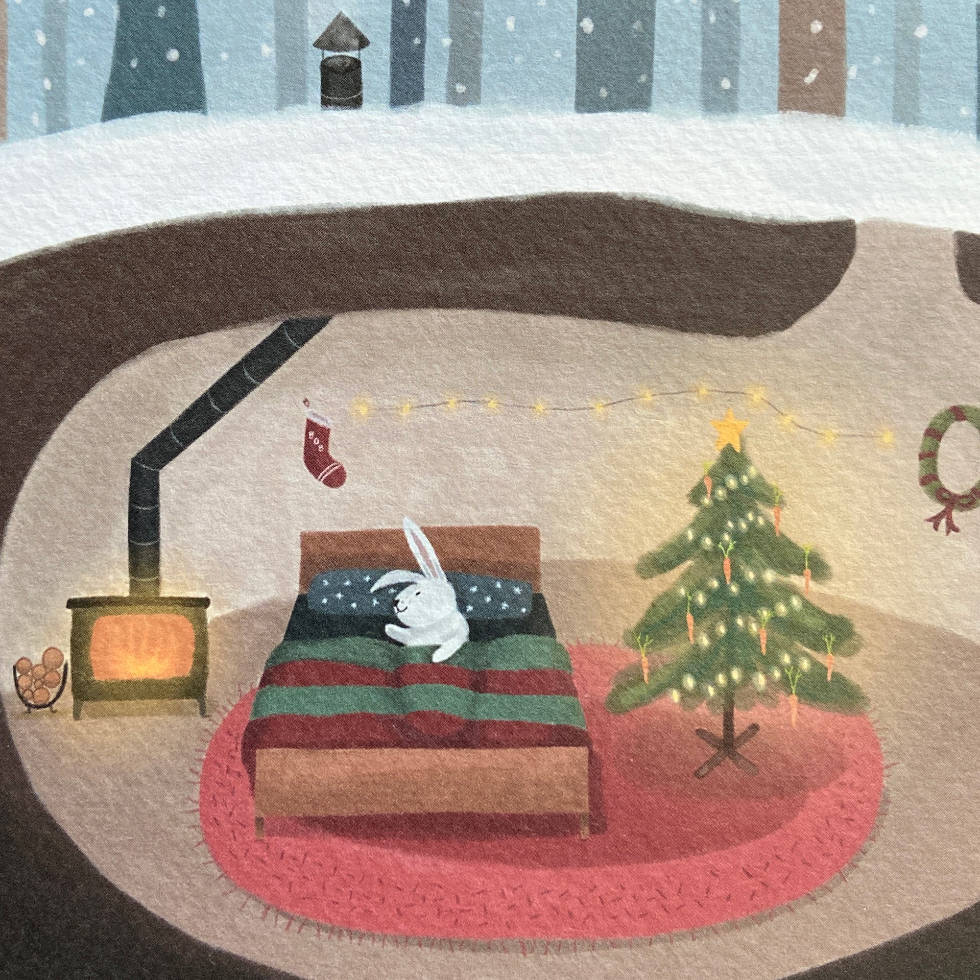 Close up Christmas card illustration of a rabbit's cozy living room with a Christmas tree, fireplace, and stockings.