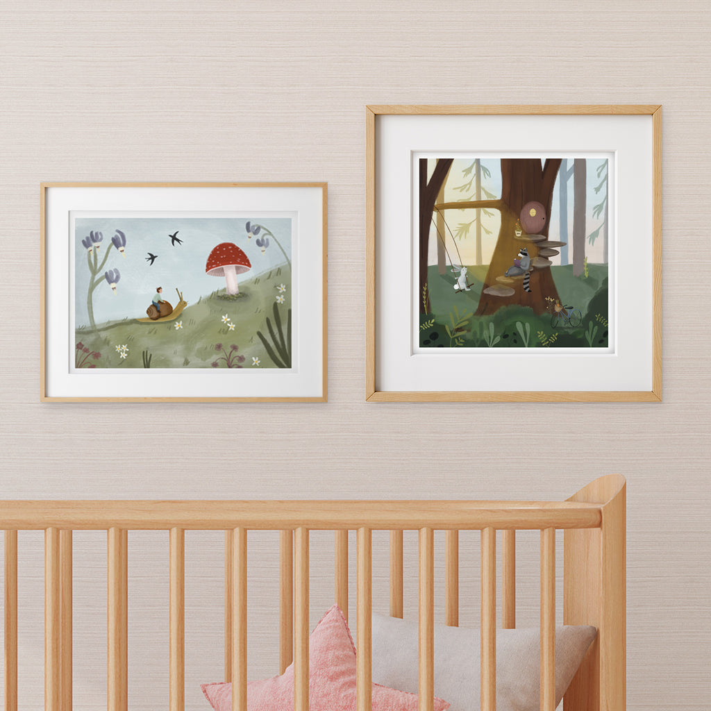 Two framed forest themed illustrations on a wall above a crib in a woodland creature nursery.
