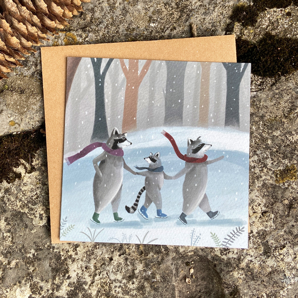 Winter greeting card with raccoons ice skating on a pond in snowy forest, on a stone background