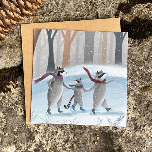 Winter greeting card with raccoons ice skating on a pond in snowy forest, on a stone background