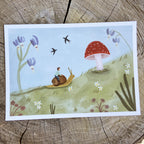 Art print with a child riding a snail, a mushroom, and flowers on a wooden surface.