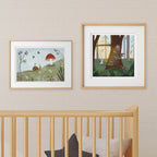 Two framed cute animal art prints on a nursery wall above a crib with a neutral background