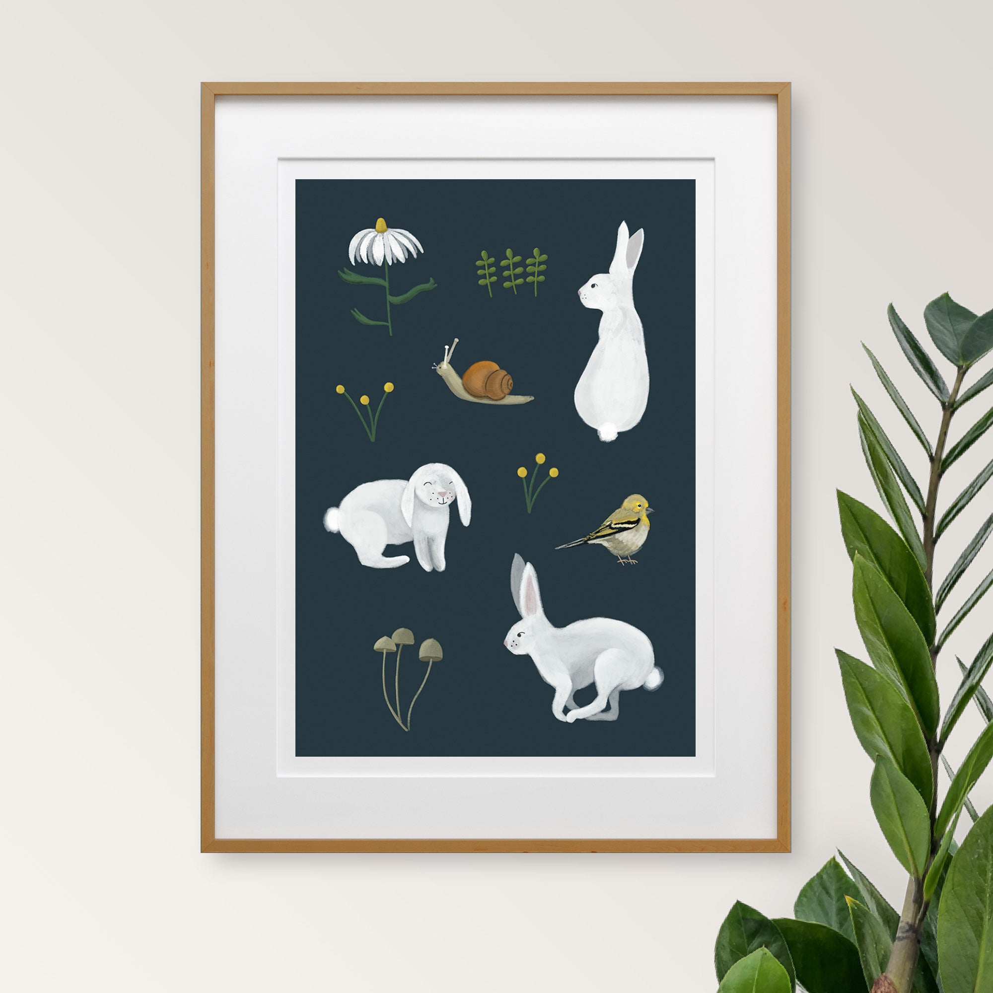 Framed artwork with illustrations of rabbits, snail, bird, and plants on a dark charcoal gray background.