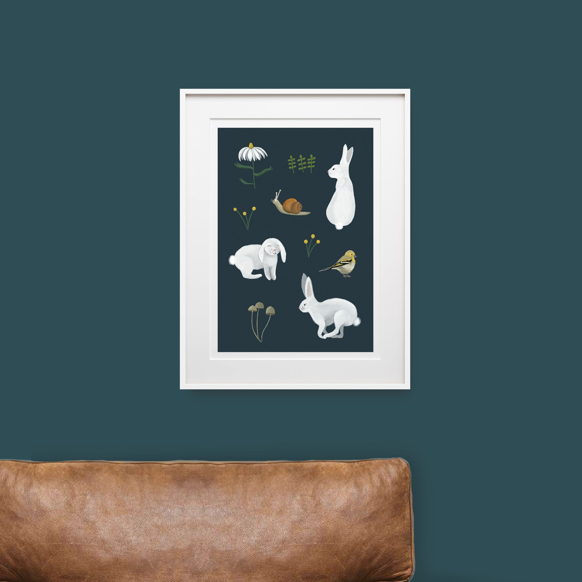 Framed artwork with illustrations of animals and plants on a dark blue wall above a brown sofa.