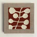 A square woven wall hanging or tapestry with a textured beige linen border and a central rust red square featuring an abstract cream leaf or vine pattern.