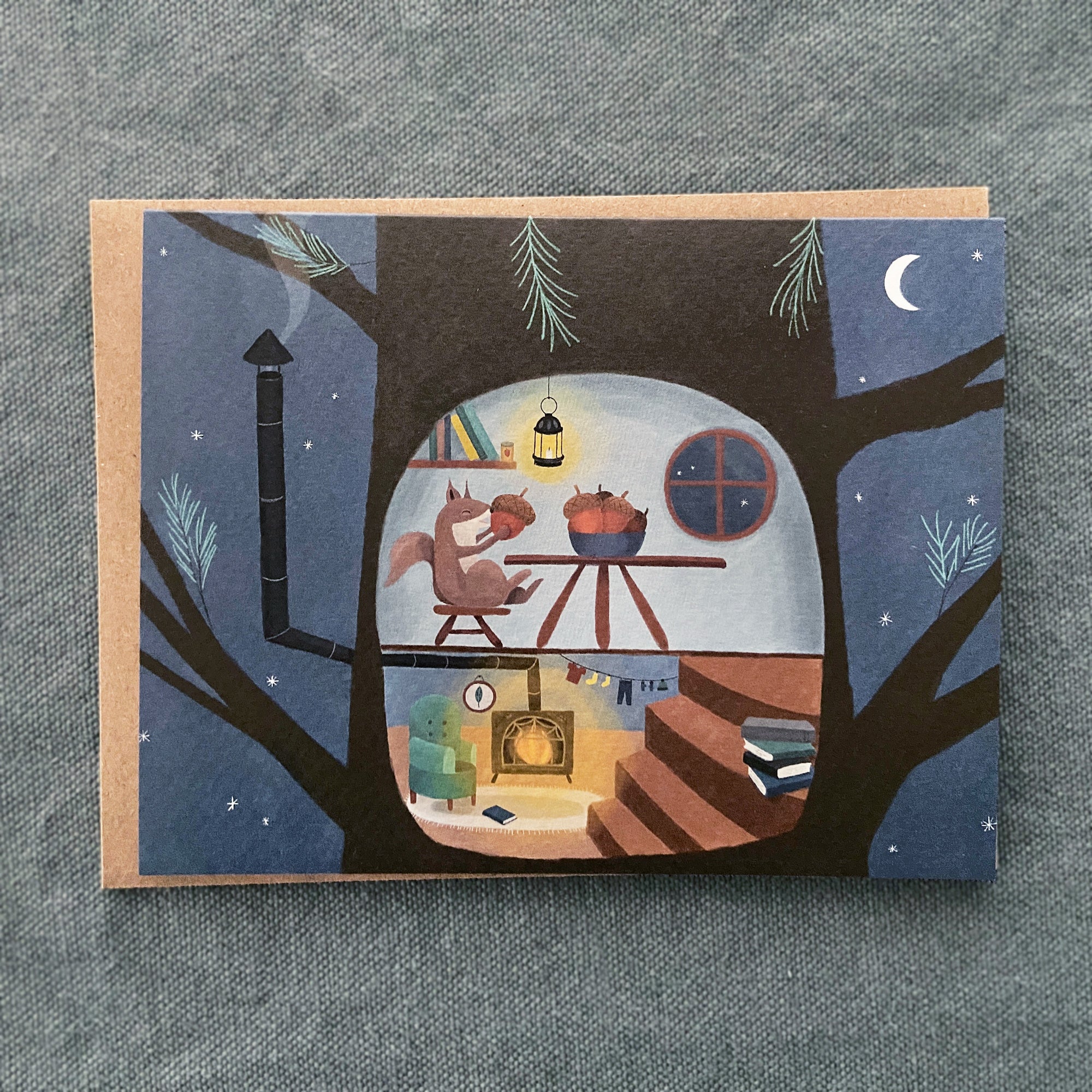 Illustrated greeting card with a squirrel in a cozy treehouse eating acorns on a textured gray background