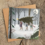 Holiday greeting card with illustration of bunnies carrying a Christmas tree in a snowy forest.