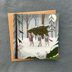 Christmas card with illustration of rabbits carrying a Christmas tree in a snowy woods.